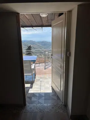 an open door leading to a balcony with a table at Odou Off-grid in Odhou