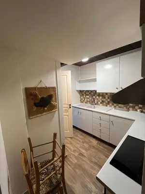 a kitchen with white cabinets and a table and chairs at Odou Off-grid in Odhou