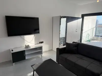a living room with a black couch and a flat screen tv at CEASAR RESORT STUDIO Consus in Aglantzia