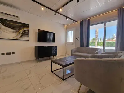 a living room with couches and a flat screen tv at Modern House in Touristic Pyla - Oroklini! in Larnaka