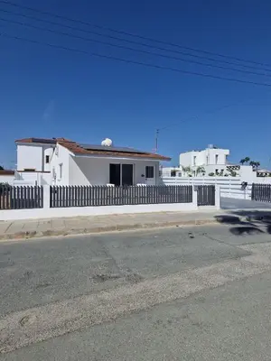 a white house with a fence next to a street at Modern House in Touristic Pyla - Oroklini! in Larnaka
