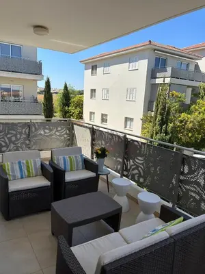a balcony with chairs and tables and a building at Cozy 2-Bedroom Beach Flat in Paralimni