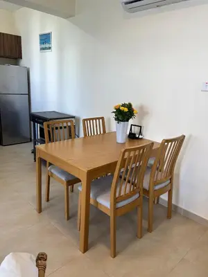 a wooden dining room table with chairs and a vase with flowers at Cozy 2-Bedroom Beach Flat in Paralimni