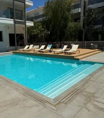 a large swimming pool with lounge chairs and a building at Cozy 2-Bedroom Beach Flat in Paralimni