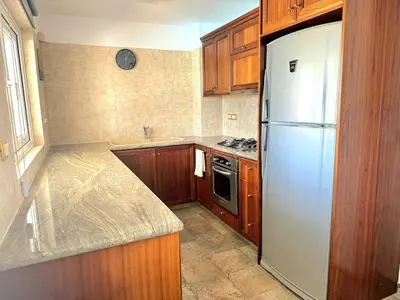 a kitchen with a white refrigerator and wooden cabinets at Serenity Pool & Garden Villa in Limassol