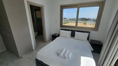 a bedroom with a bed with white sheets and a window at Suburban Escape in Limassol