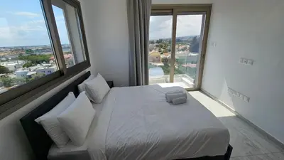 a bedroom with a bed and large windows at Suburban Escape in Limassol