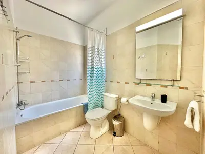 a bathroom with a toilet and a sink and a tub at Cydonia Gardens Maisonette with shared pool in Limassol