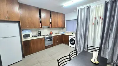 a kitchen with wooden cabinets and a white refrigerator at Dasoudi beach apartment in Limassol