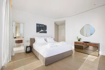 a white bedroom with a large bed and a table at Trilogy Limassol Seafront in Limassol