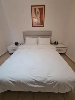 a large white bed in a bedroom with two night stands at At Patara Site, the heart of Kyrenia in Aglantzia