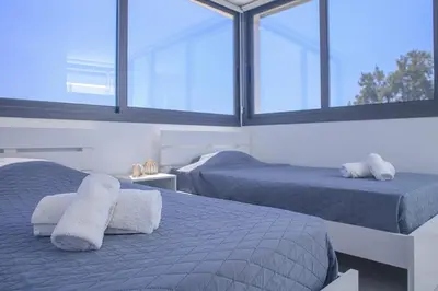 two beds in a room with windows at Elegant penthouse in City Centre in Larnaka