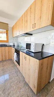 a kitchen with wooden cabinets and a black counter top at Central City Rooms in Larnaka