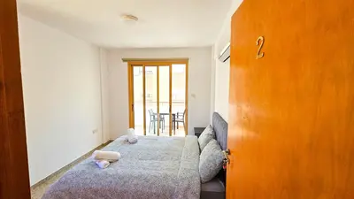a bedroom with a bed and a wooden door at Central City Rooms in Larnaka