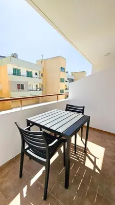 a black table and a chair on a balcony at Central City Rooms in Larnaka