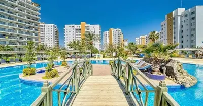 a bridge over a swimming pool with buildings in the background at Marcellus in Larnaka