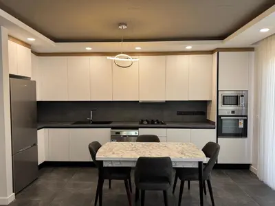a kitchen with white cabinets and a table and chairs at Kervansaray Comfort in Ayii Trimithias
