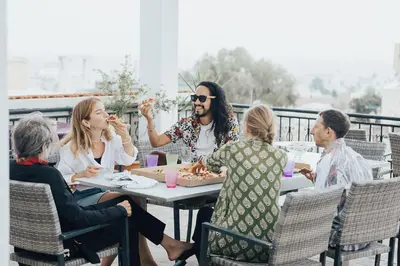 a group of people sitting around a table eating food at One Love One World Ayia Napa Square Hostel in Ayia Napa