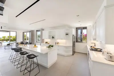 a kitchen with white cabinets and bar stools at Villa JoJo Seafront in Ayia Napa