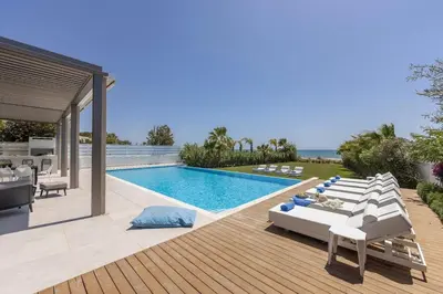 a pool with chaise lounge chairs and a swimming pool at Villa JoJo Seafront in Ayia Napa