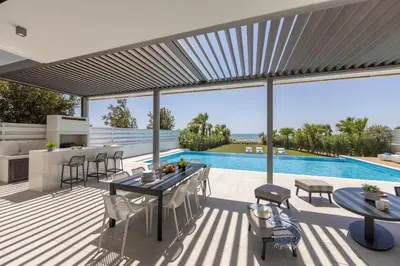 a patio with a table and chairs and a pool at Villa JoJo Seafront in Ayia Napa