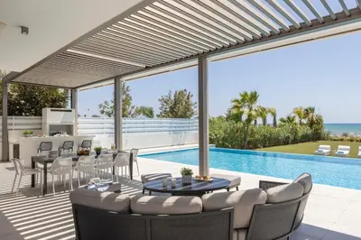 a patio with a table and chairs and a pool at Villa JoJo Seafront in Ayia Napa