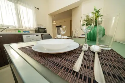 a table with a plate and glasses and a fork and spoon at 2 bedroom flat in Nicosia