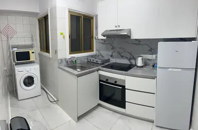 a white kitchen with a sink and a washer and dryer at Tiffany 11 Finikoudes in Larnaka