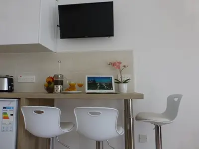 a kitchen with white chairs and a counter with a laptop at STAY Paradise Sands Studio in Ayia Napa