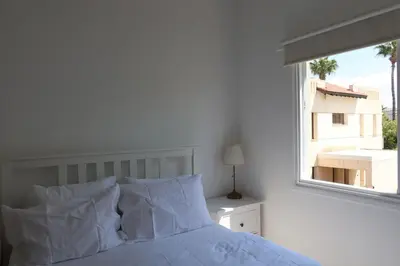 a white bedroom with a bed and a window at Cozy Holiday Apartment with Balcony in Pyla