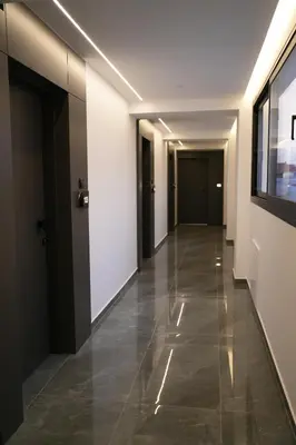 a hallway with white walls and a hallway with black doors at Zen City Suites in Larnaka