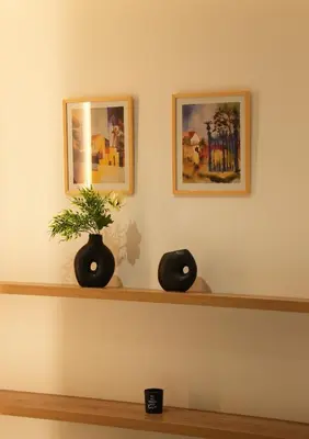two black vases sitting on a shelf with two pictures at Zen City Suites in Larnaka