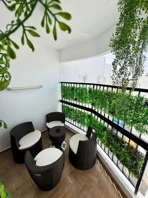 a room with chairs and a balcony with plants at Gold Feather 2Bedroom Center Location and Pool in Ayia Napa