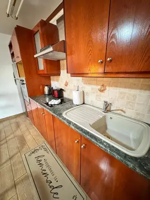 a kitchen with a sink and wooden cabinets at Gold Feather 2Bedroom Center Location and Pool in Ayia Napa