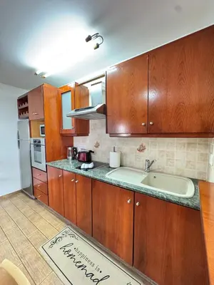 a kitchen with wooden cabinets and a sink at Gold Feather 2Bedroom Center Location and Pool in Ayia Napa