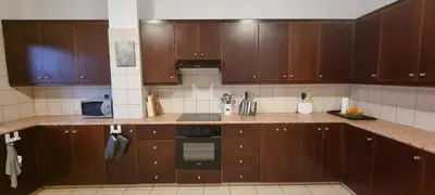a kitchen with wooden cabinets and a counter top at The Cozy Home Stay in Larnaca in Larnaka