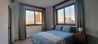a bedroom with a blue bed and two windows at The Cozy Home Stay in Larnaca in Larnaka