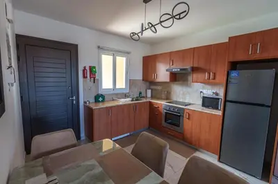 a kitchen with wooden cabinets and a table and a refrigerator at Mythical Sands Resort and Spa in Paralimni