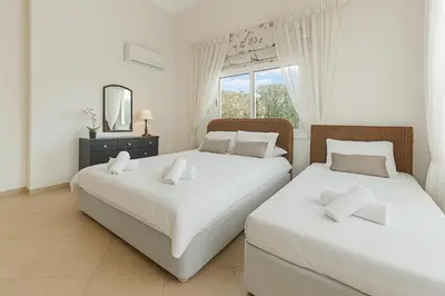 two beds in a white room with a mirror at Villa Thea, Luxury Cliff Sea View in Pissouri
