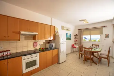 a kitchen with wooden cabinets and a table with a dining room at STAY Villa Kangaroo in Protaras