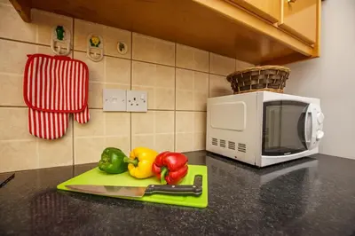 a kitchen counter with a knife and vegetables next to a microwave at STAY Villa Kangaroo in Protaras