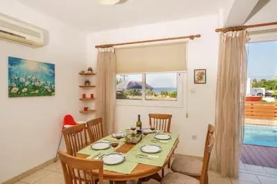 a dining room with a table and chairs and a window at STAY Villa Kangaroo in Protaras
