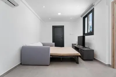 a bedroom with a bed and a couch and a window at PANATHEON - Luxury 1 & 2 bdr bungalows 300 meters from sandy beach! in Ayia Napa