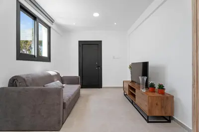 a living room with a couch and a tv at PANATHEON - Luxury 1 & 2 bdr bungalows 300 meters from sandy beach! in Ayia Napa