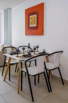 a dining room table with four chairs and a painting at Pernera One Suites in Pernera Protaras in Paralimni