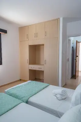 a bedroom with two beds and wooden cabinets at Pernera One Suites in Pernera Protaras in Paralimni
