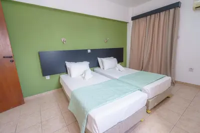 two beds in a room with green walls at Pernera One Suites in Pernera Protaras in Paralimni