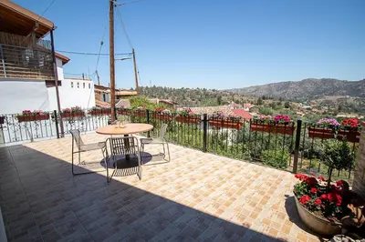 a patio with a table and chairs and flowers at Archontikon 1817 in Kaliana