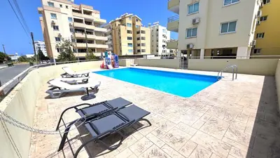 a swimming pool with two lounge chairs next to a building at Stylish 2BR Apartment with Balcony, Wifi & Pool in Larnaka
