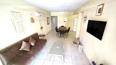 a living room with a brown couch and a table at Stylish 2BR Apartment with Balcony, Wifi & Pool in Larnaka